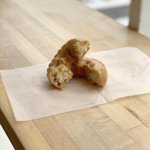 A partially eaten pastry on a piece of parchment paper, resting on a wooden table.