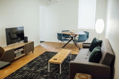 Cozy living room with a sofa, coffee table, TV, and dining area featuring a round table and blue chairs.
