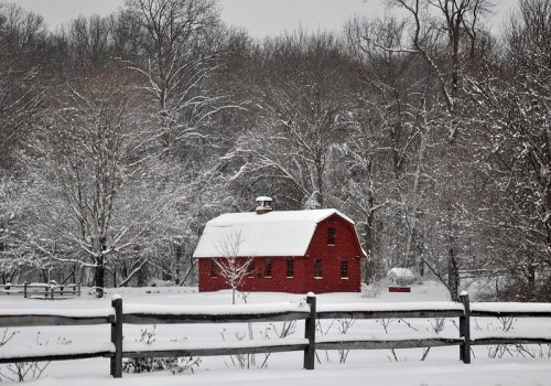 A red barn surrounded by snow-covered trees and a white landscape on a winter day.