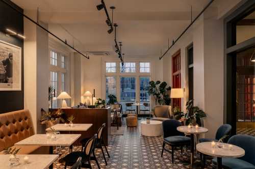 A cozy café interior with stylish seating, plants, and large windows, creating a warm and inviting atmosphere.