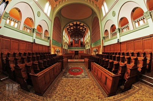 Interior of a spacious, ornate church featuring wooden pews, a patterned floor, and a grand organ at the back.