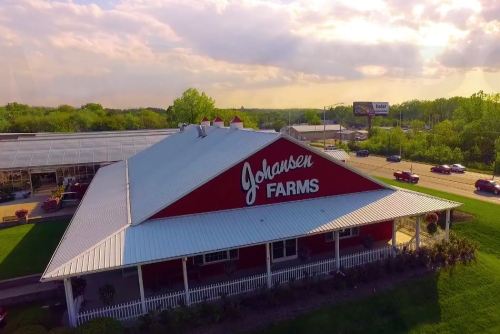 Aerial view of Johansen Farms, a red barn-style building surrounded by greenery and a clear sky.