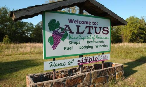 Sign welcoming visitors to Altus, Arkansas, highlighting its wineries, shops, restaurants, and the "simple life."