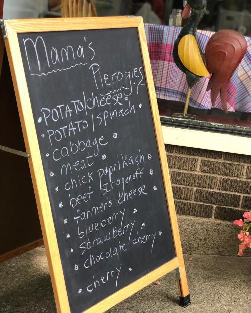 A chalkboard menu listing various types of pierogies, including flavors like potato, cabbage, and fruit options.