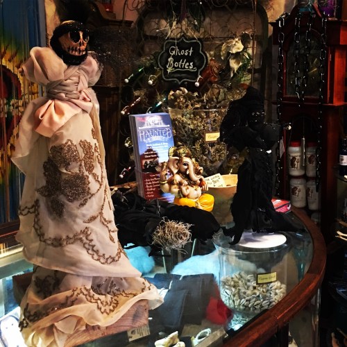 A display of spooky decorations, including a ghostly figure and a statue of Ganesha, in a mystical shop setting.