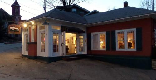 A cozy, illuminated building at dusk, featuring large windows and a welcoming entrance.
