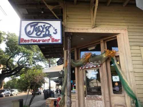 Sign for Joey K's Restaurant Bar on a wooden building, decorated with green and gold accents.