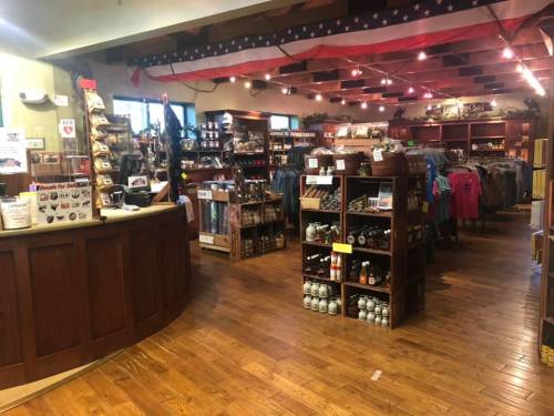 Interior of a gift shop featuring wooden shelves, merchandise displays, and an American flag decor. Warm, inviting atmosphere.