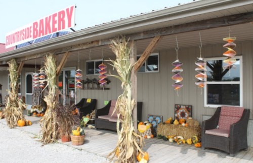 A cozy bakery storefront decorated with autumn decor, including pumpkins and hanging ornaments.
