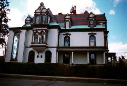 A large, ornate Victorian-style house with colorful roofing and intricate architectural details.
