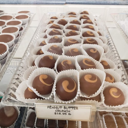 A display of peanut butter crunch chocolates in paper cups, priced at $18.19 per pound.