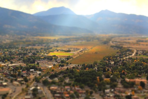 Aerial view of a valley surrounded by mountains, with fields and small towns visible in the foreground.