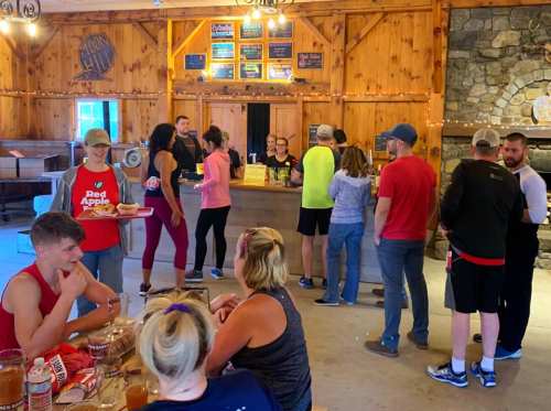 A busy rustic café with people ordering at the counter and others seated at tables, enjoying food and drinks.
