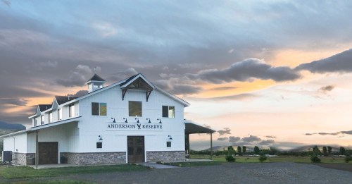 A white barn-style building with "Anderson Reserve" sign, set against a cloudy sunset sky and open landscape.