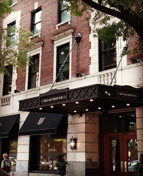 Exterior of the Read House hotel, featuring brick walls, large windows, and a stylish entrance canopy.