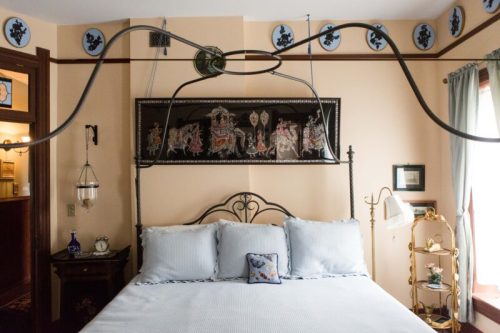 A cozy bedroom featuring a metal bed frame, decorative wall art, and vintage accents in warm tones.