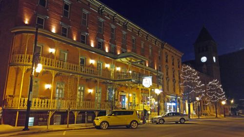 Historic brick building illuminated at night, with decorative lights and a clock tower in the background.