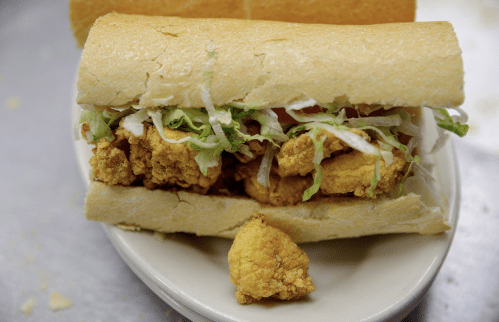 A sandwich filled with crispy fried chicken, lettuce, and tomato, served on a soft hoagie roll.