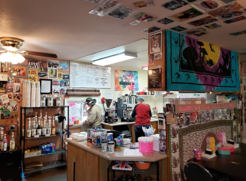 A cozy café interior with colorful decor, a counter, and staff preparing drinks in a vibrant, eclectic atmosphere.