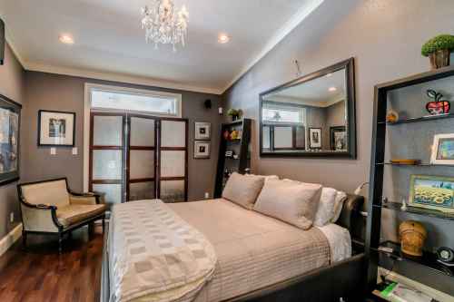 Cozy bedroom with a large bed, elegant chandelier, and stylish decor, featuring a mirror and bookshelves.