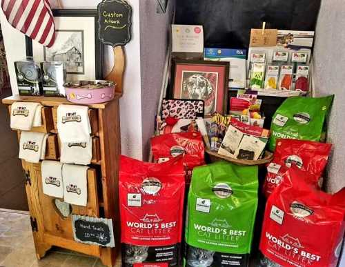 A display featuring custom artwork, pet supplies, and bags of World's Best Cat Litter in a cozy shop setting.