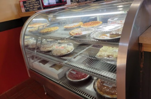 A display case filled with various pies and desserts, showcasing a variety of flavors and styles.