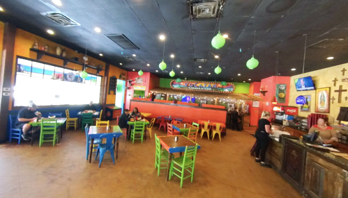 Colorful restaurant interior with vibrant chairs, a lively atmosphere, and patrons enjoying their meals.
