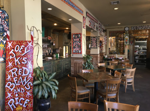 Colorful restaurant interior with decorated walls, wooden tables, and chairs, featuring a vibrant, artistic atmosphere.