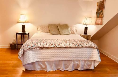 Cozy bedroom with a double bed, decorative pillows, two lamps, and wooden flooring.