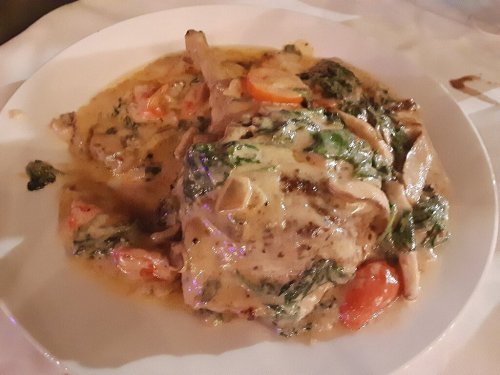A plate of creamy chicken with spinach and tomatoes, served in a rich sauce.