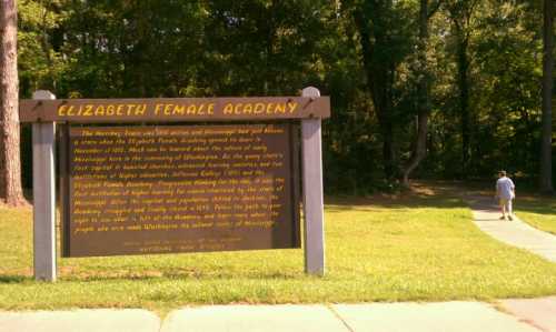 Sign for Elizabeth Female Academy with historical information, surrounded by trees and a path leading away.