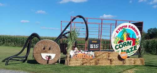 A festive display for Etch Farms' Corn Maze, featuring hay bales, a smiling face, and Halloween decorations.