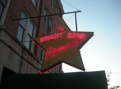 Neon sign of the Bright Star Restaurant in the shape of a star, glowing against a twilight sky.