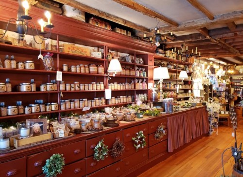 A cozy shop interior with wooden shelves filled with jars, candles, and decorative items, creating a warm atmosphere.