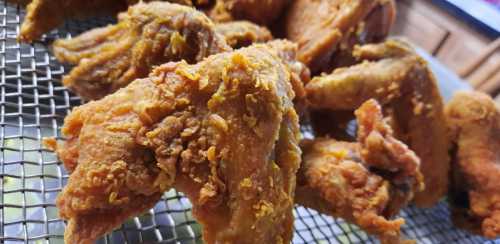 Crispy, golden-brown fried chicken wings arranged on a wire rack.