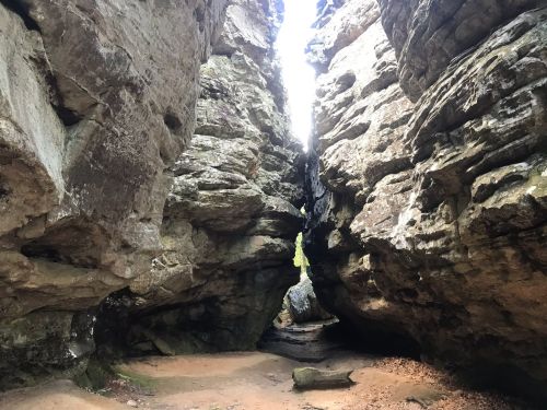 A narrow canyon between towering rock formations, with sunlight streaming through the top.