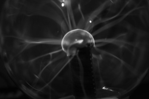 A close-up of a plasma globe, showing electric arcs and a glowing sphere at the center, in black and white.