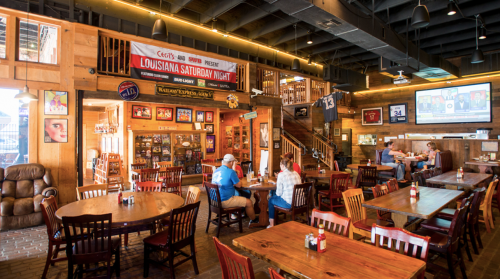 A cozy restaurant interior with wooden decor, tables, and sports memorabilia, featuring a banner for "Louisiana Saturday Night."