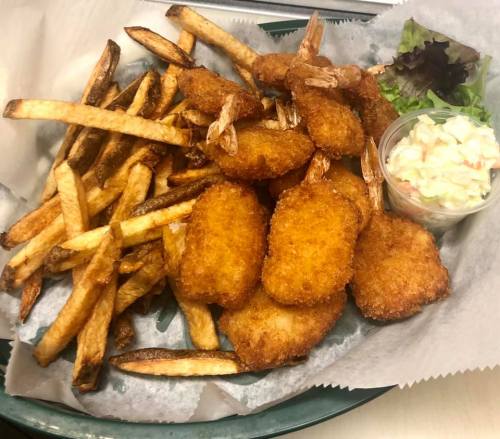 A plate of golden fried shrimp and crispy French fries, served with a side of coleslaw and lettuce.