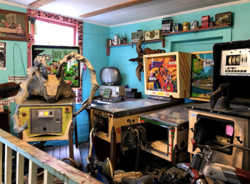 A colorful room filled with vintage arcade machines, retro decor, and eclectic memorabilia.