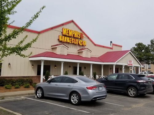 Exterior of Memphis Barbecue Co. restaurant with a red roof and parked cars in front.