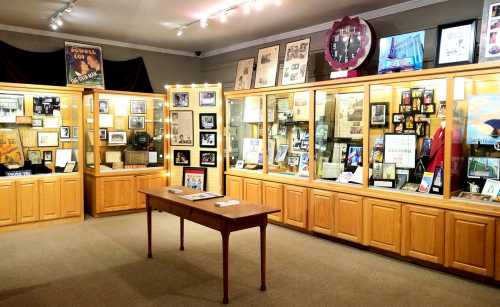 A museum display featuring wooden cabinets filled with framed photos, documents, and memorabilia.