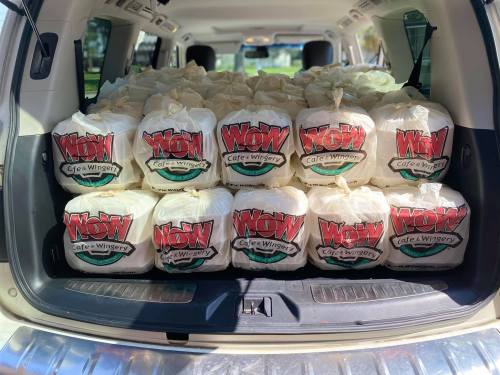 A car trunk filled with neatly stacked bags from Wow Cafe & Wingery, ready for delivery or pickup.