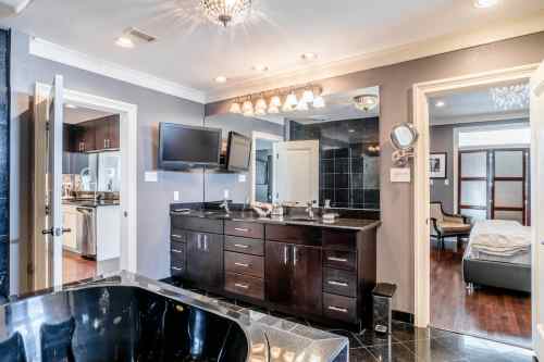 Modern bathroom featuring a dark vanity, large mirror, and a freestanding tub, with stylish lighting and hardwood floors.