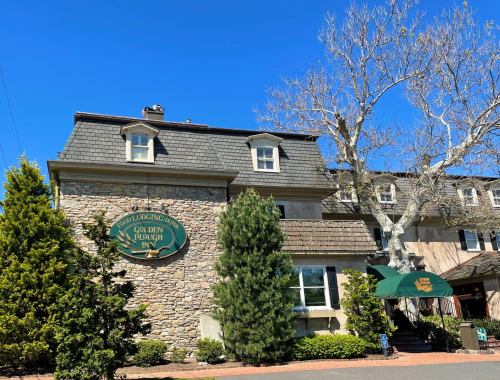 Exterior of the Golden Plough Inn, featuring stone walls, a green awning, and clear blue skies.