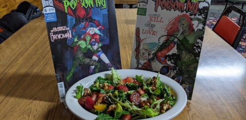 A bowl of salad with various toppings, flanked by two comic book covers featuring Poison Ivy.