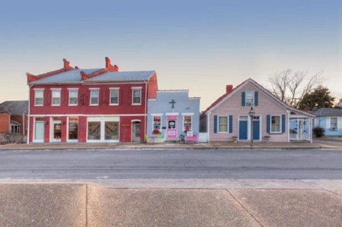 A row of colorful historic buildings along a quiet street, featuring red, blue, and pink facades.