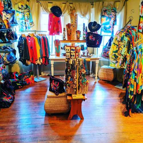 A colorful boutique filled with vibrant clothing and accessories displayed on racks and tables in a cozy setting.