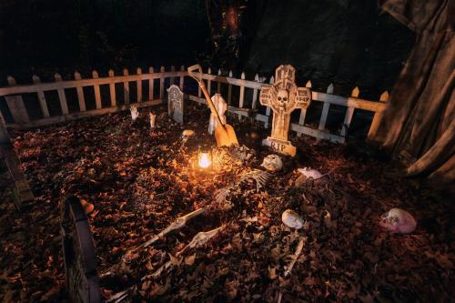 A spooky graveyard scene with tombstones, skeletons, and a candle surrounded by fallen leaves at night.