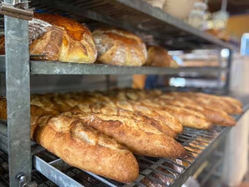 Freshly baked loaves of bread cooling on metal racks in a bakery.